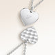 Close-up of two heart-shaped pendants in silver – rippled front and polished back with an engraved initial