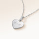 Angled close-up of minimalist heart-shaped heart pendant in silver with white zircons and space for personalized engraving on the front and back