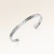 Close-up of minimalist bangle bracelet in silver with rippled wave surface and space for personalized engraving