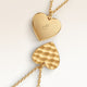 Close-up of minimalist heart-shaped heart pendant in gold with rippled wave surface and space for engraving on back