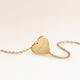 Back of a heart-shaped gold necklace with a personal engraved date