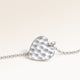 Close-up of minimalist heart-shaped heart pendant in silver with rippled wave surface and space for engraving on back