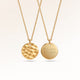 Personalized round gold necklace with rippled wave surface and space for engraving of text, coordinates or handwriting on the back