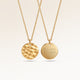 Personalized round gold necklace with rippled wave surface and space for engraving of text, coordinates or handwriting on the back