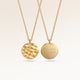 Personalized round gold necklace with rippled wave surface and space for engraving of text, coordinates or handwriting on the back