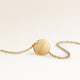 Back of a round gold necklace with a personal engraved date