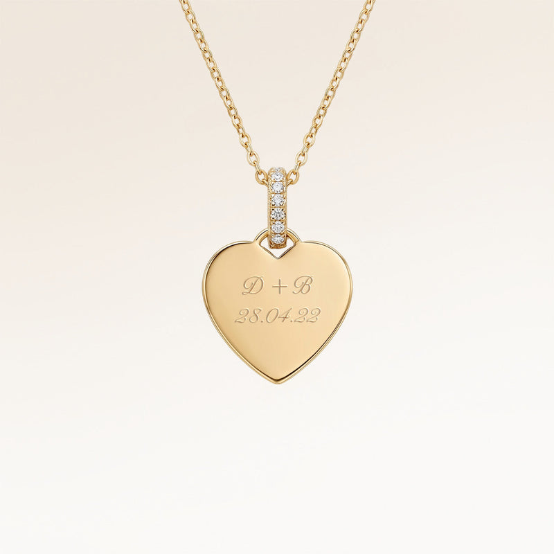 Close-up of minimalist heart-shaped heart pendant in gold with white zircons and space for personalized engraving on the front and back