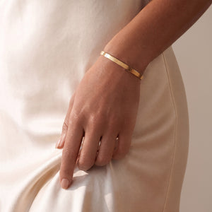 Model mit personalisiertem Armreif in Gold mit Platz für eine Gravur von Text oder Koordinaten