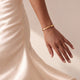 Model in cremefarbenem Satinkleid mit personalisiertem Bangle-Armreif in Gold mit eingraviertem Datum