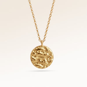 Nahaufnahme des minimalistischen runde Anhängers in Gold mit weich geschmolzene Optik und Platz für Gravur hinten