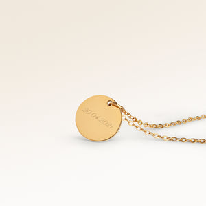 Personalized round gold necklace with rippled wave surface and space for engraving of text, coordinates or handwriting on the back