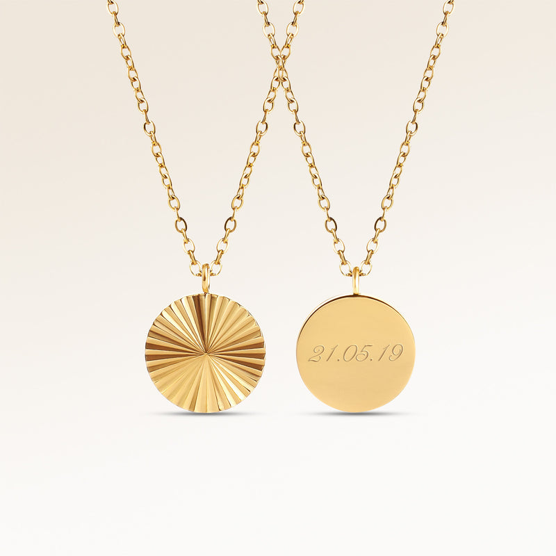 Personalized round gold necklace with ribbed sunburst pattern and space for engraving of text, coordinates or handwriting on the back